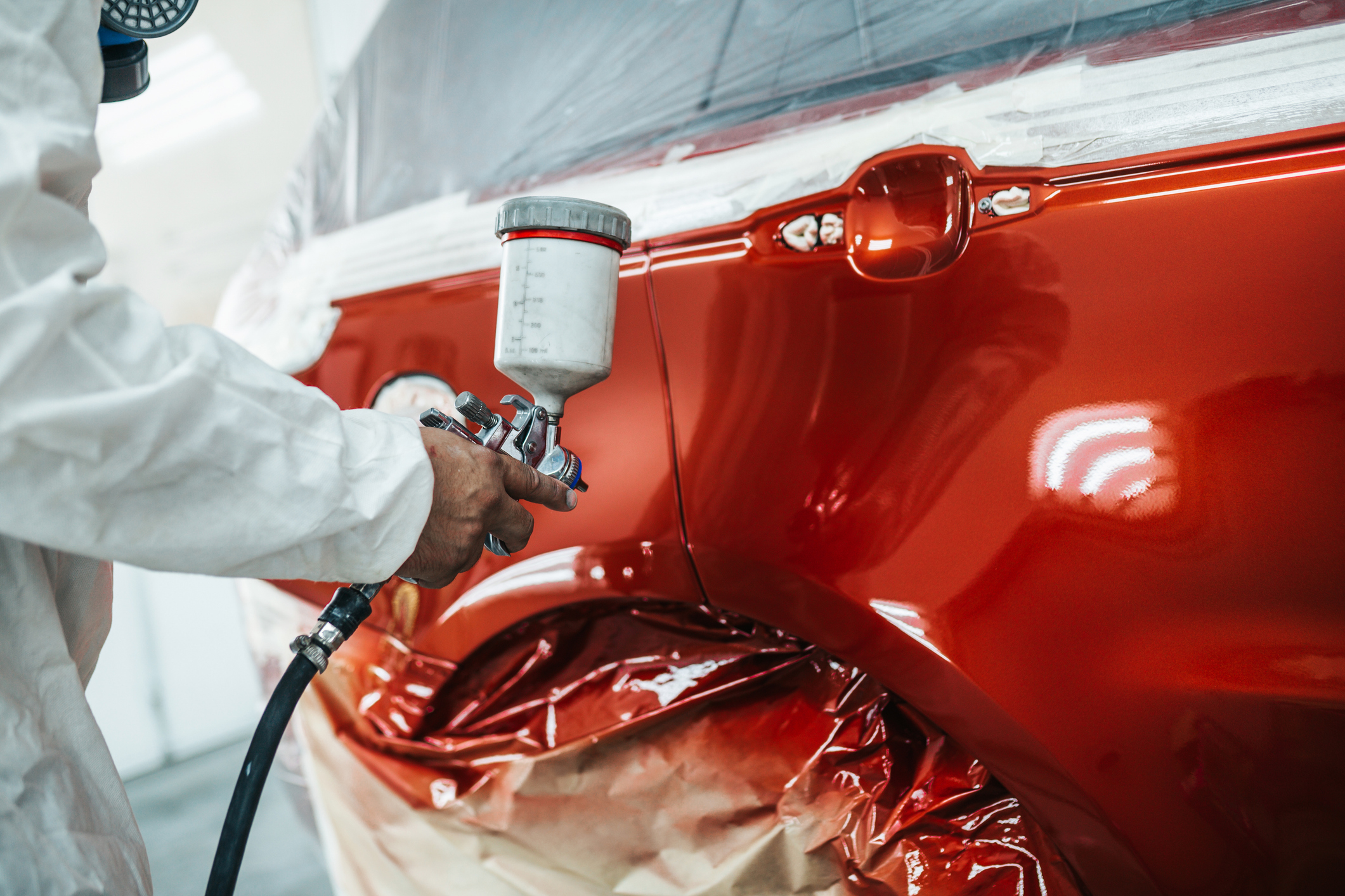 Car being spray painted in red.
