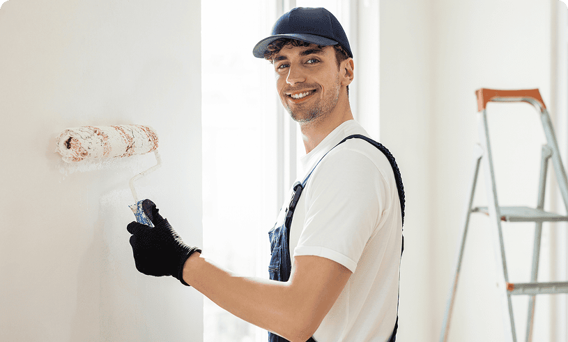 Man painting wall with roller smiley face.