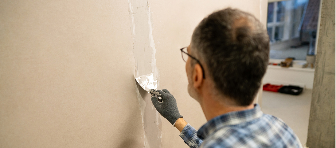 Man repairing wall with putty knife.