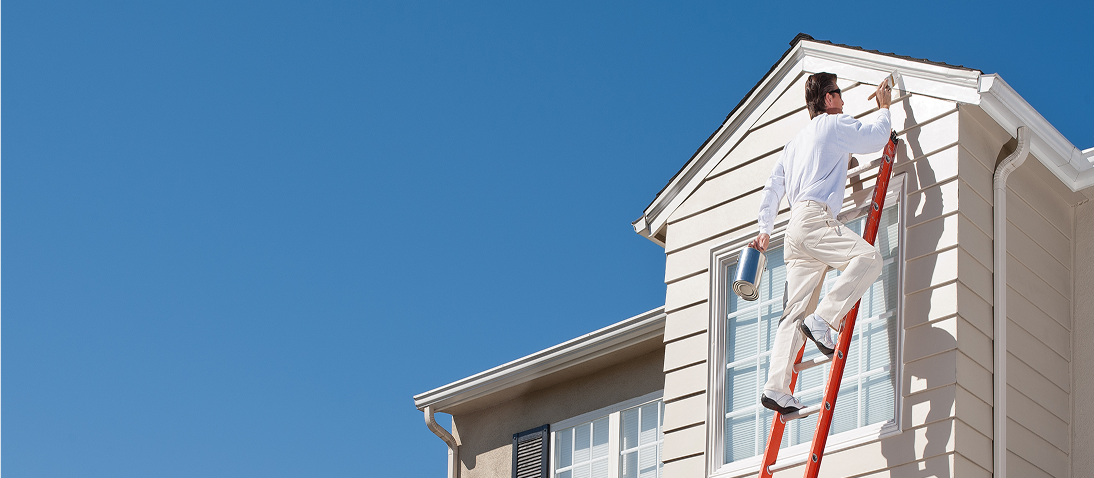 Person painting house on a ladder outside.