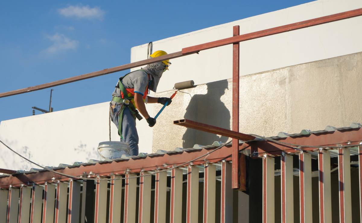 Man in safety gear painting building exterior