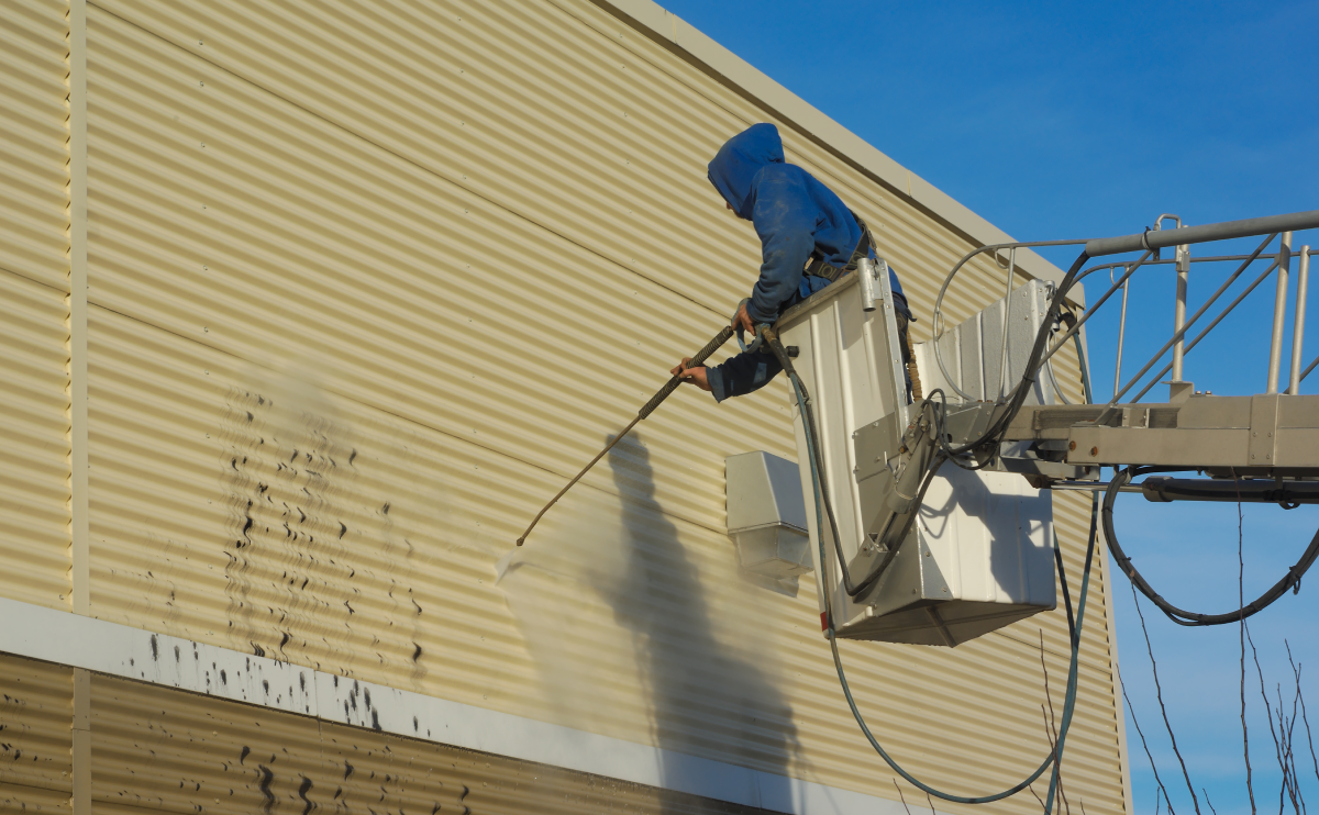 Person pressure washing building exterior