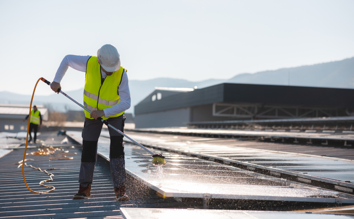 Technician washing solar panels on roof