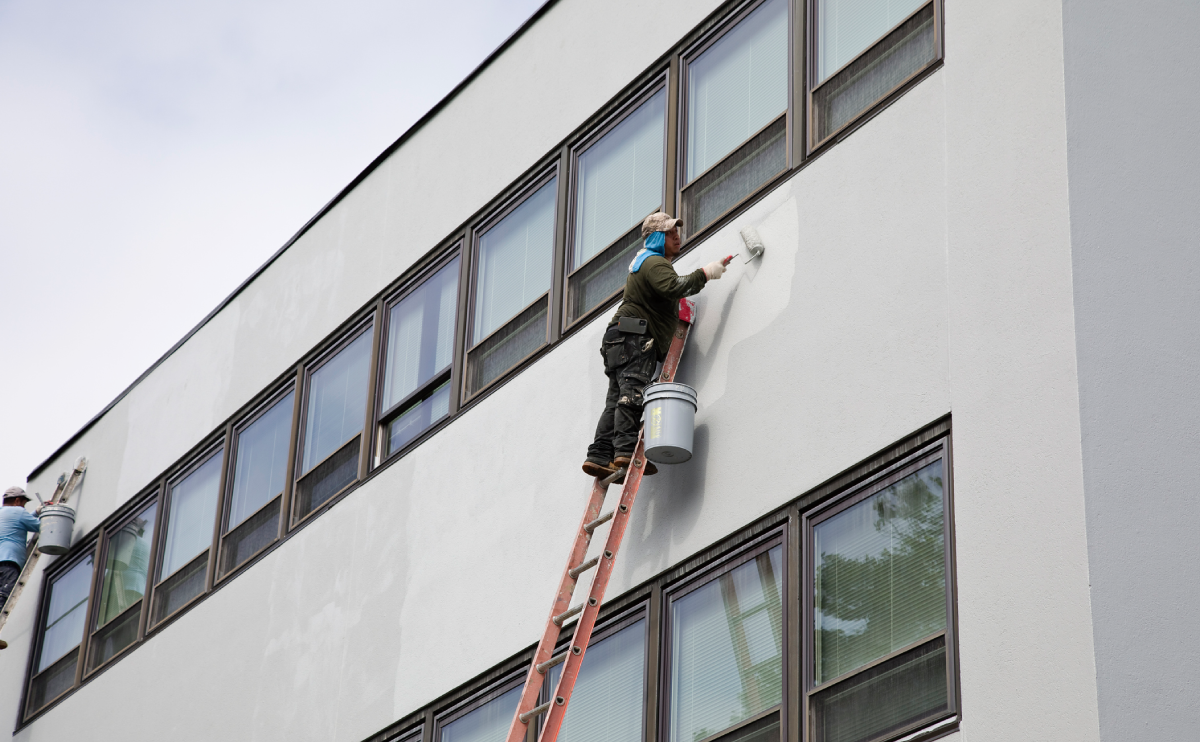 Painter on ladder painting building wall