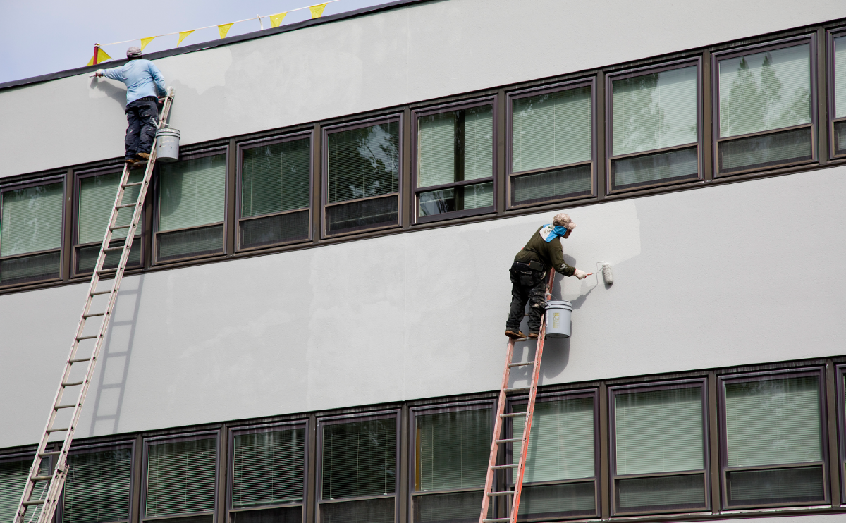 Painters on ladders painting building facade