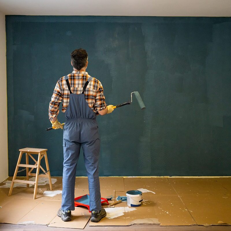 Man painting wall with paint roller