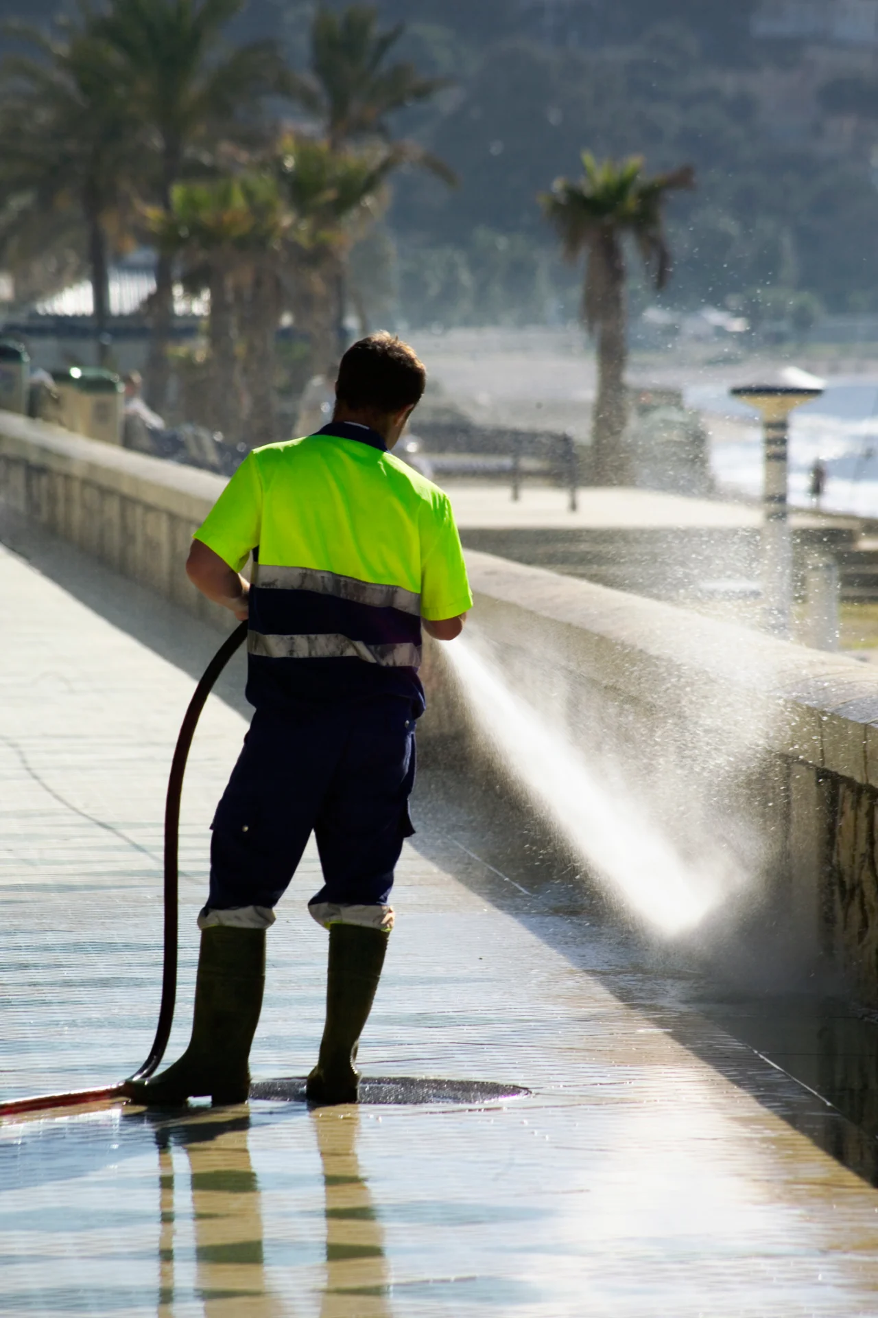 Person washing walkway near the beach