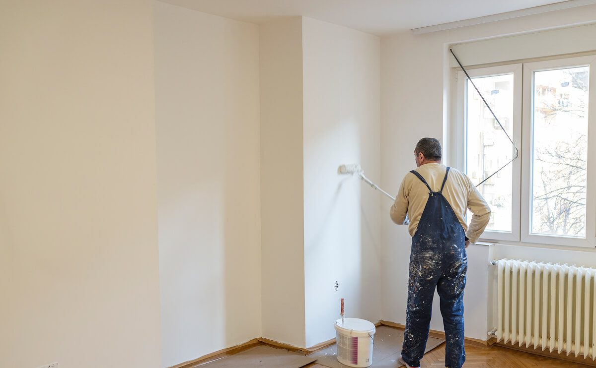 Person painting a room with a roller.