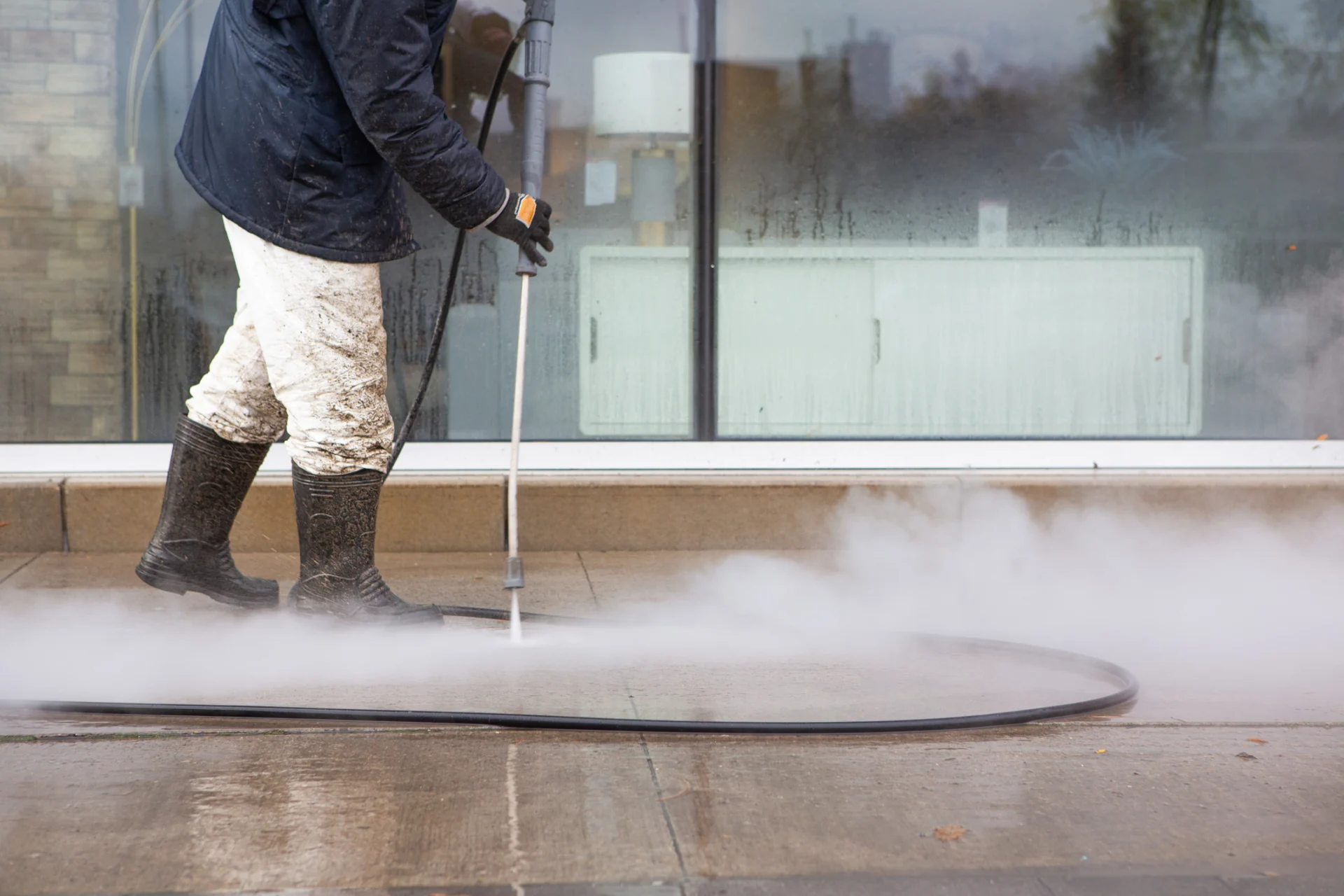 Worker cleaning pavement with power washer