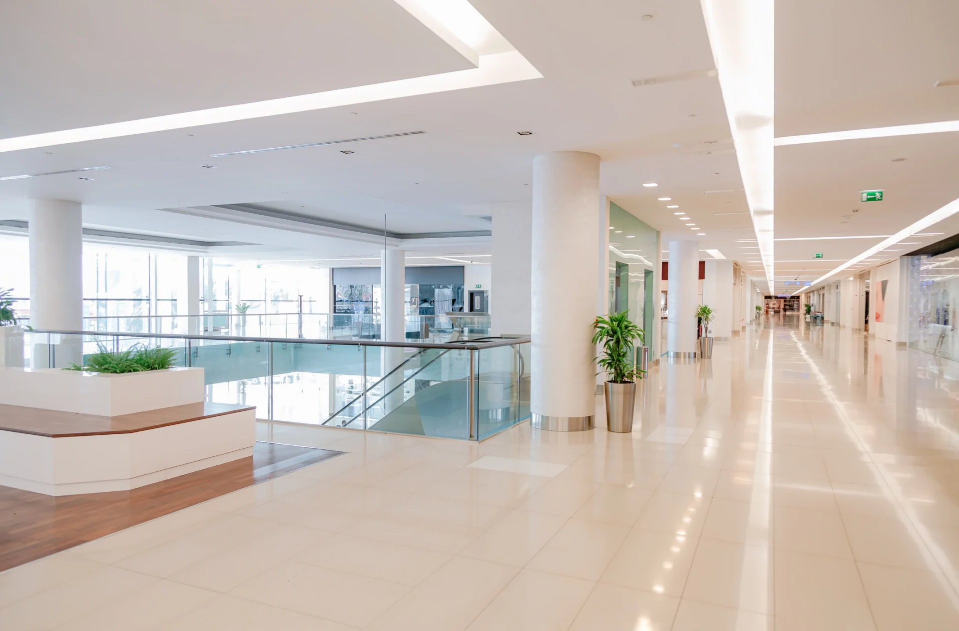 Bright Empty Corridor in Modern Shopping Mall Interior with Glass Railings and Copy Space.