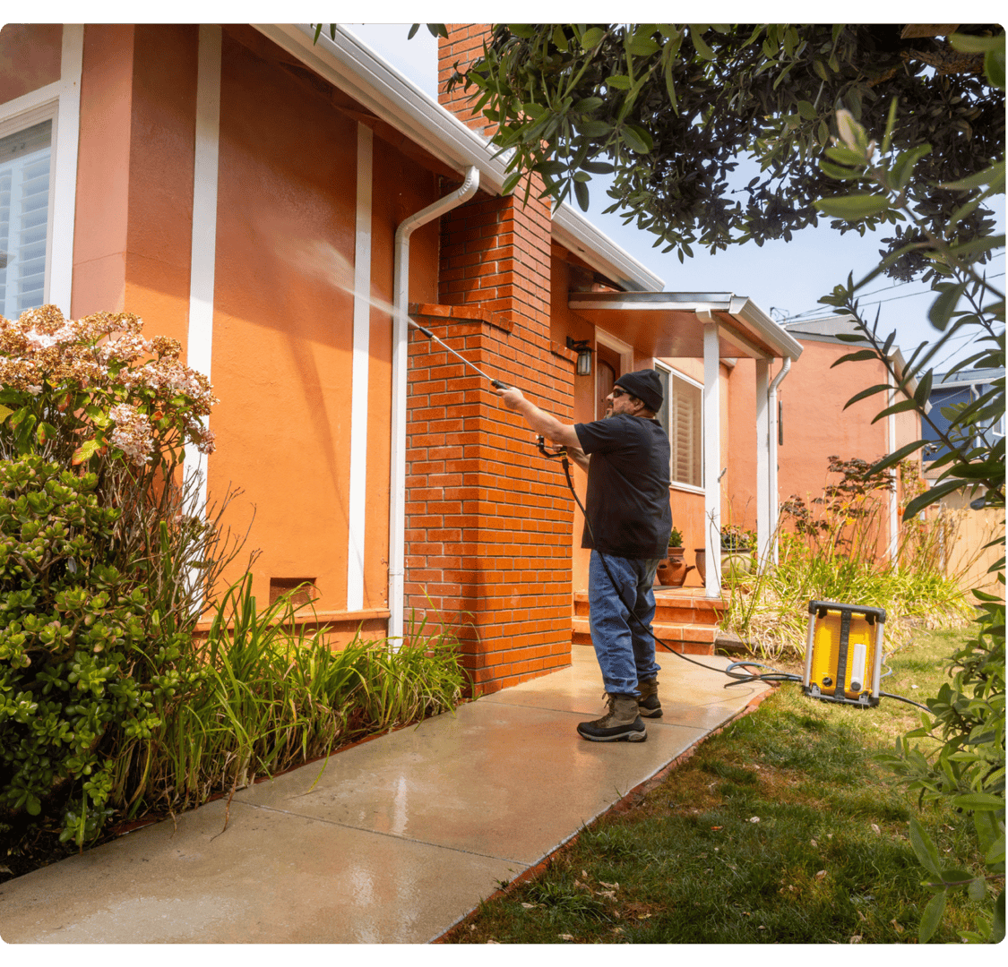 Man pressure washing house exterior