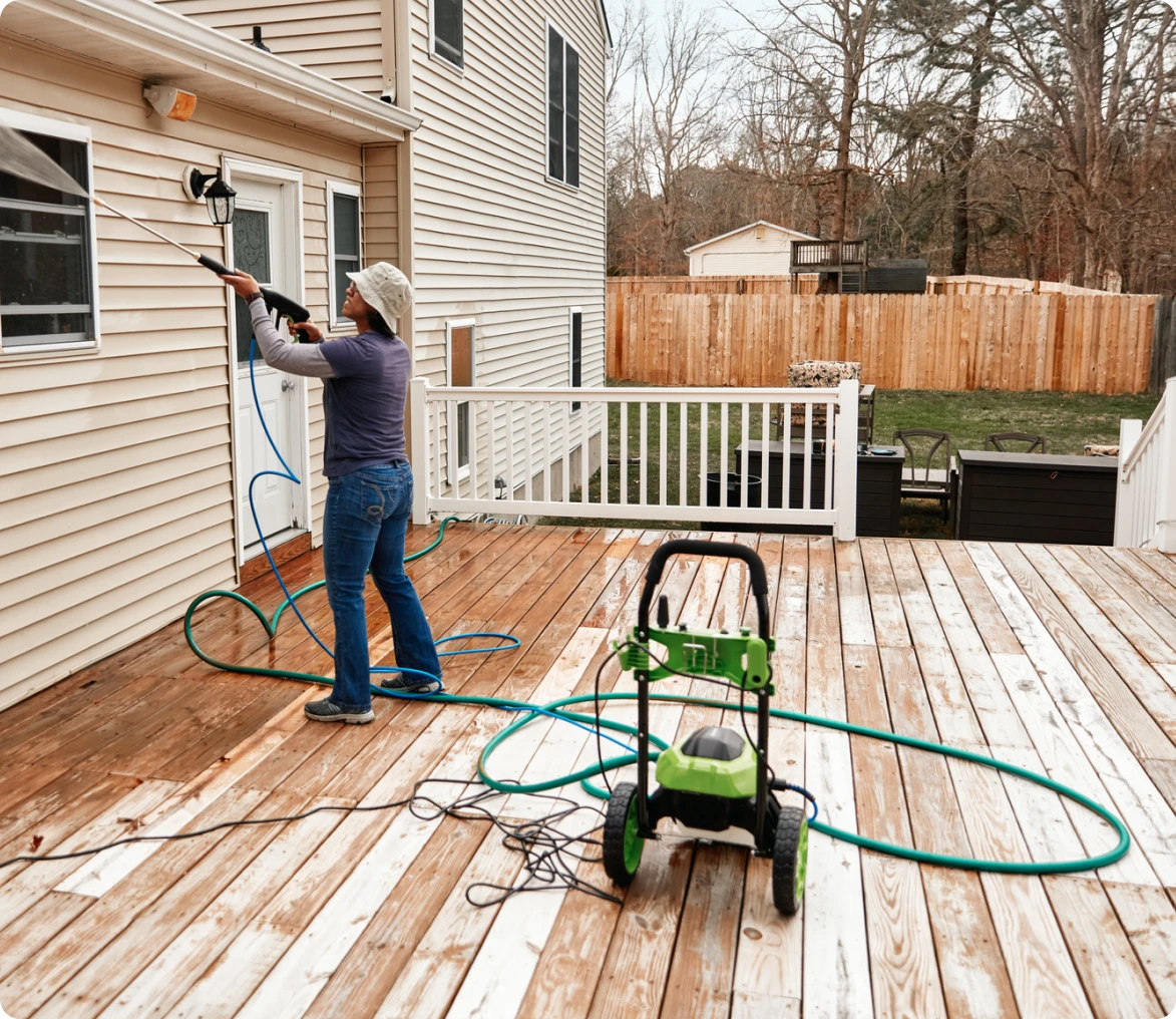 Woman using pressure washer on patio